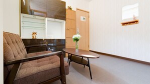 Et hotelværelse med en træstol, et lille bord med en vase blomster og et træskab.