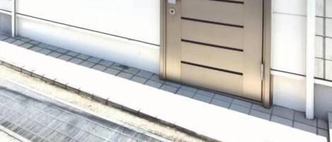 Puerta metálica cerrada con un letrero, una placa pequeña y una rejilla metálica en el suelo.