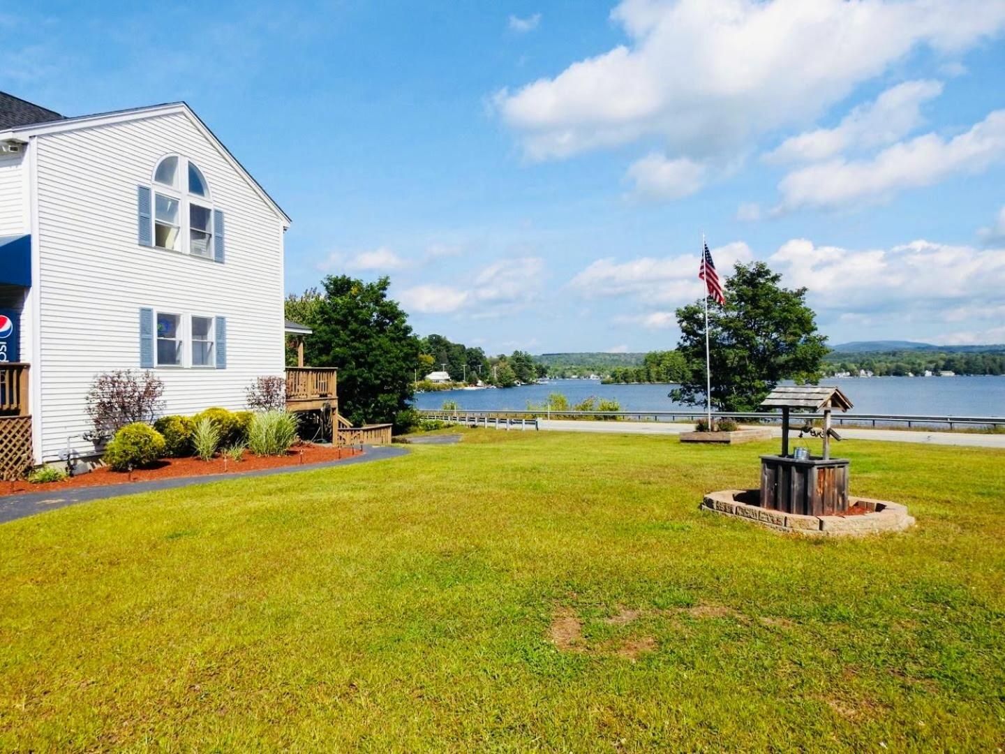 A white house with a deck, a flag, and a lake view.