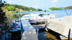A dock with boats, a jet ski, and a covered area. - Winnisquam Lake Inn (Tilton)