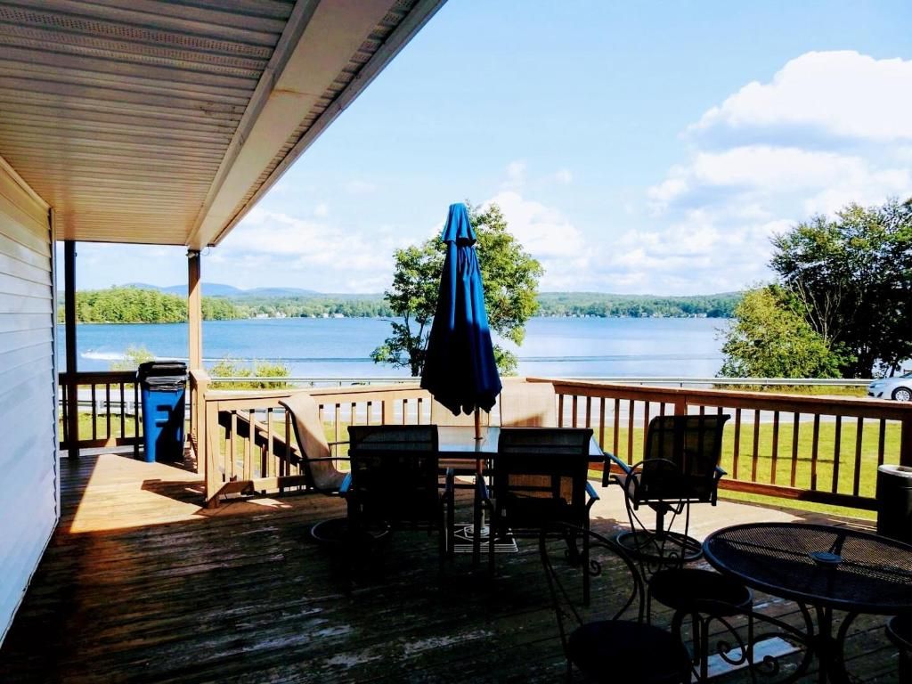 A wooden deck with outdoor seating, overlooking a lake.