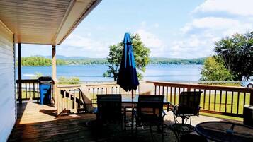 A wooden deck with outdoor seating, overlooking a lake.