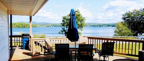 A wooden deck with outdoor seating, overlooking a lake.