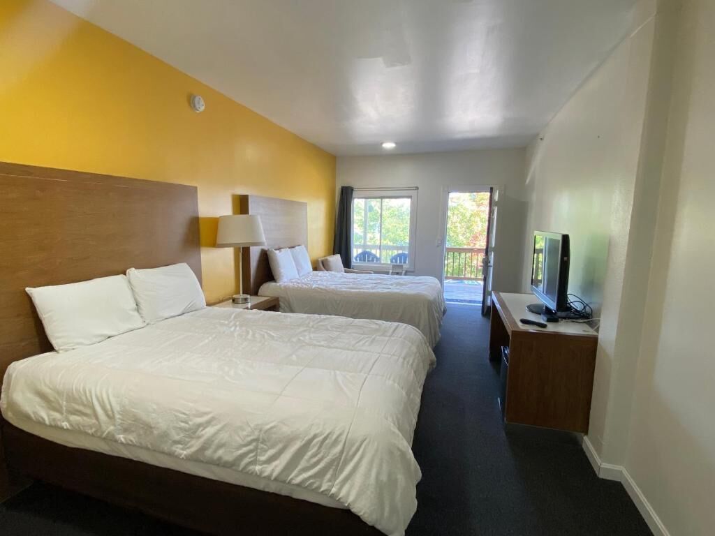 A hotel room with two beds, a television, and a window with a view.