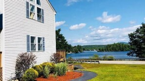 A white house with a large window and a view of a lake. - Winnisquam Lake Inn (Tilton)
