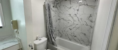 A bathroom with a toilet, bathtub, and shower curtain.