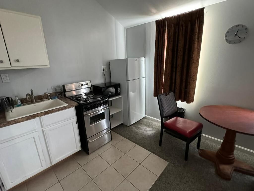 A compact kitchen with white cabinets, a stove, a microwave, and a refrigerator.