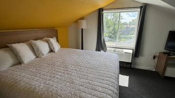 Une chambre d’hôtel avec un grand lit, un bureau, une télévision et une fenêtre avec des rideaux.