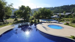 A large outdoor swimming pool with multiple circular sections and surrounding greenery. - Samba Bluewater Resort (Olongapo)