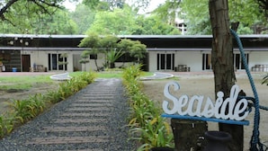 A pathway leading to a building with a 'Seaside' sign, surrounded by greenery and potted plants. - Samba Bluewater Resort (Olongapo)