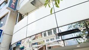 A multi-story building with a modern facade, a visible entrance with glass doors, and a sign indicating the name and address. - Yokohama Sakuragicho Town Hotel 24 (Yokohama)