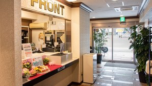 A reception desk with a 'FRONT' sign, a bulletin board, and a welcome mat. - Yokohama Sakuragicho Town Hotel 24 (Yokohama)