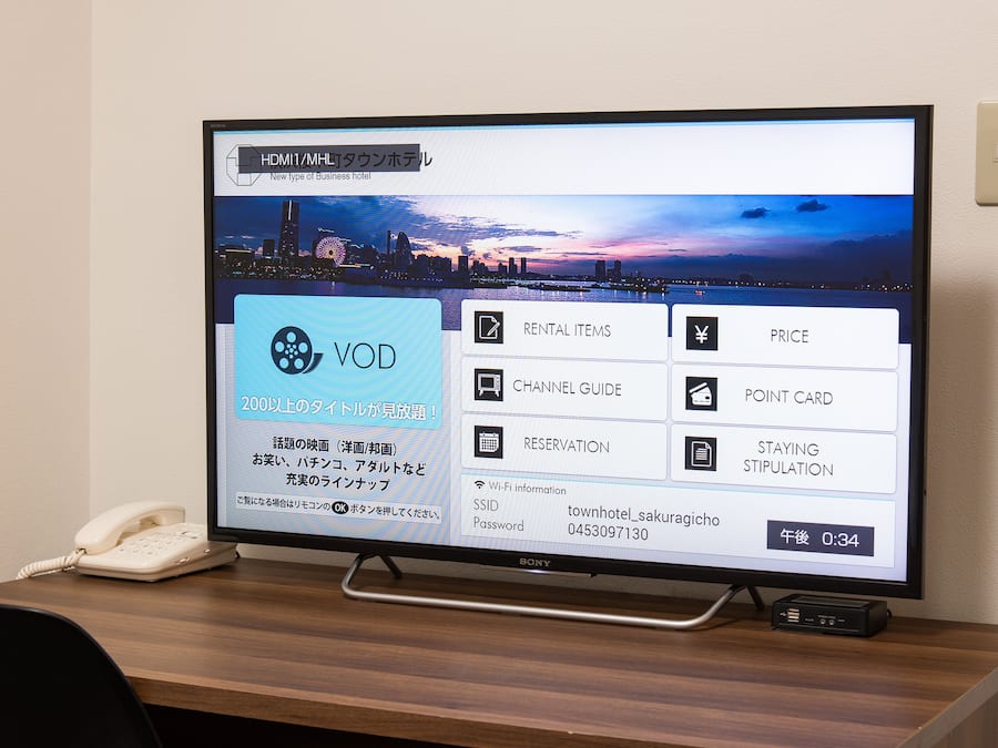 A hotel booking interface on a computer monitor with a cityscape background.