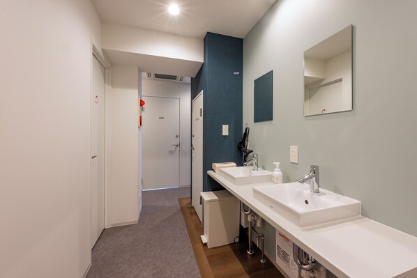 Un baño moderno con dos lavamanos, un espejo y zona de ducha.