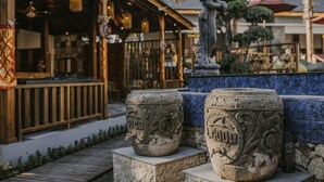 A stone fountain with intricate carvings, a wooden bench, and a statue in a courtyard. - L.Good Lembongan Island Villas (Lembongan Island)