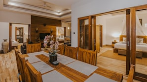 A spacious room with a wooden dining table, a large mirror, and a bed with a canopy. - L.Good Lembongan Island Villas (Lembongan Island)