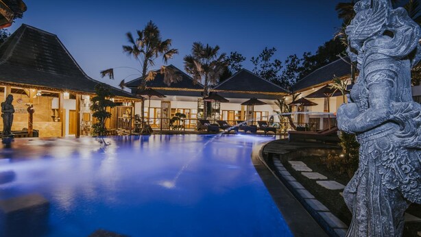 A pool area with a statue, a building with a thatched roof, and palm trees. - L.Good Lembongan Island Villas (Lembongan Island)