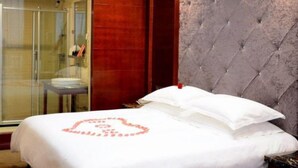 A hotel room with a large bed, a glass shower enclosure, and a tufted headboard. - Yongzhou Binhu Hotel (Yongzhou)