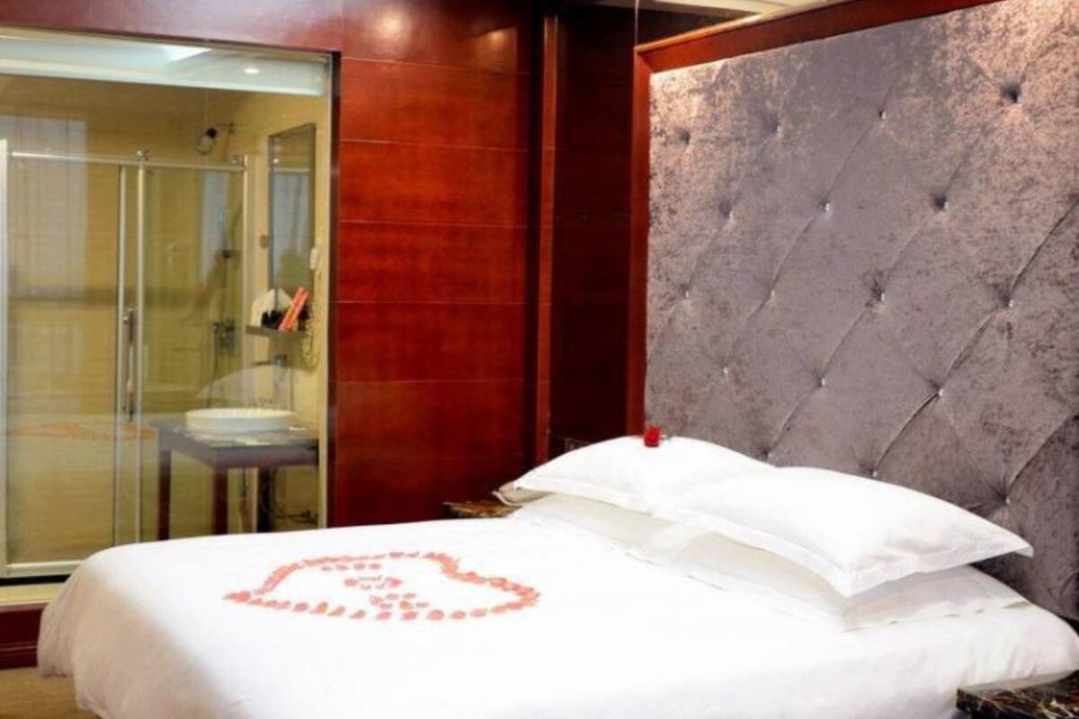 Ein Hotelzimmer mit einem großen Bett, einer Duschkabine aus Glas und einem gepolsterten Kopfteil.