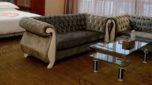 A hotel room with a tufted sofa, a glass coffee table, and a bed with a white headboard. - Yongzhou Binhu Hotel (Yongzhou)