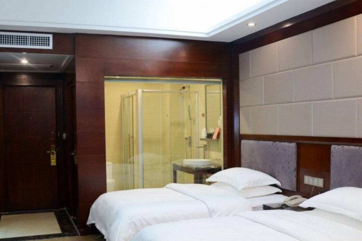 Ein Hotelzimmer mit zwei Betten, einer Dusche und einem kleinen Tisch.