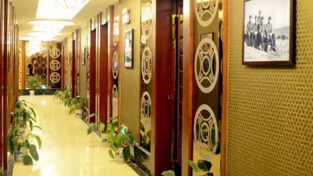 A hotel corridor with a long, polished floor, wooden paneling, and circular wall decorations. - Yongzhou Binhu Hotel (Yongzhou)