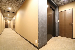 Pasillo de hotel con techo estampado, pared texturizada y puerta de madera con la indicación '307'.