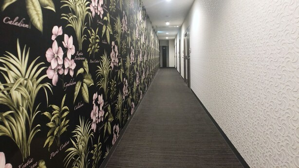 En hall med ett blommigt tapetmönster och ett heltäckningsmatta på golvet.