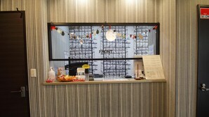 A reception desk with a window view of scaffolding, a clock, and a menu board. - Tokyo Tourist Inn (Tokyo)