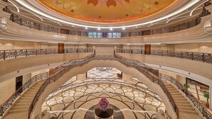 A multi-level atrium with a central circular seating area, multiple balconies, and ornate railings.