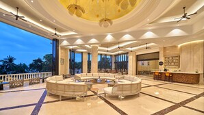 A spacious lobby with a central seating area, large windows, and a decorative ceiling.