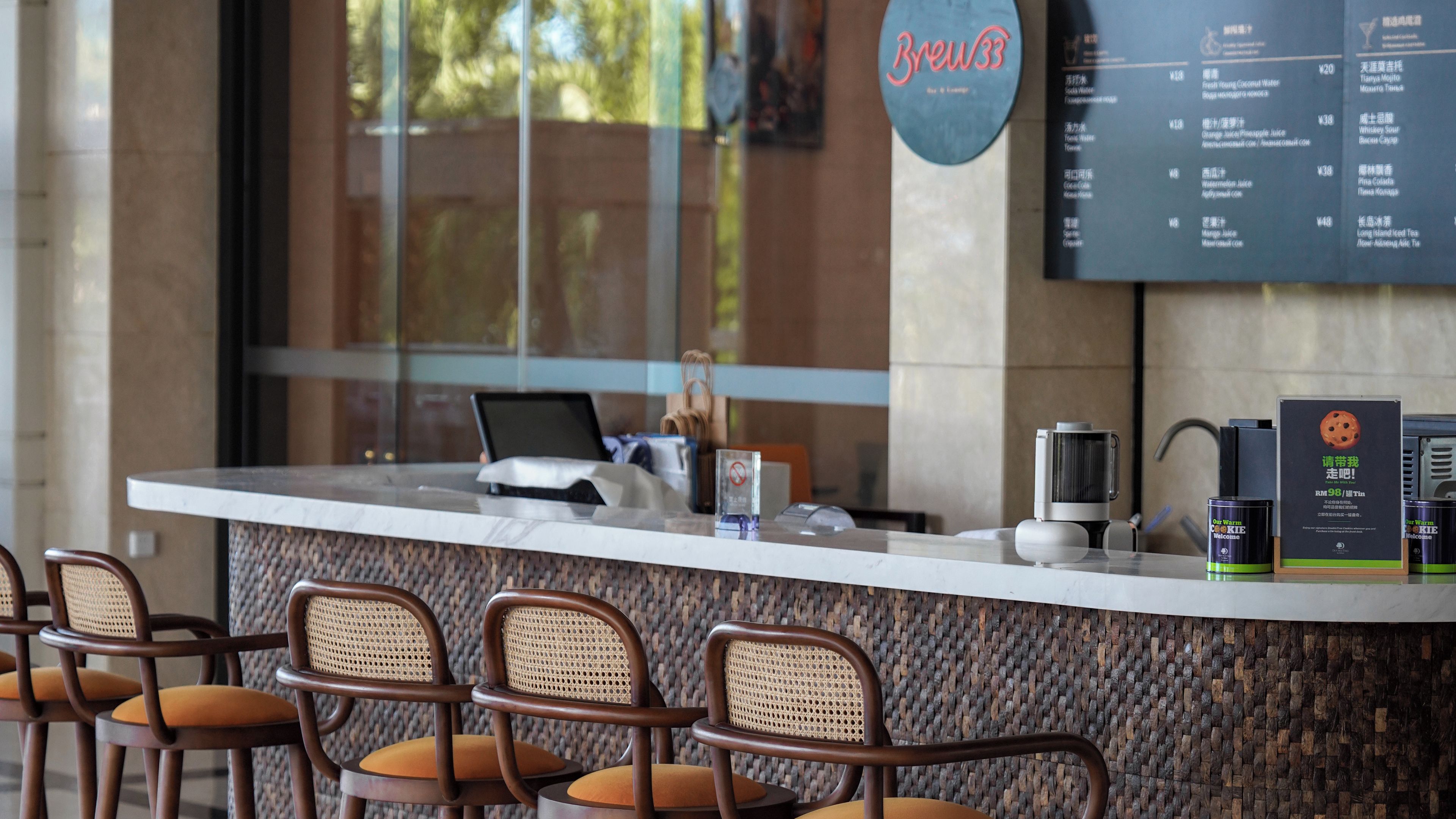 A counter with a menu board, a coffee machine, and wicker chairs.