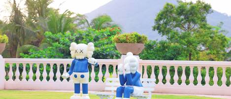 Two statues on a white bench with a balustrade in the background.