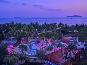 A resort with a pool area, palm trees, and a view of the sea. - DoubleTree by Hilton Sanya Bay (Sanya)
