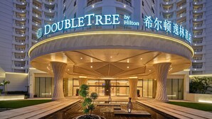 A hotel entrance with a curved facade, large columns, and a central water feature.