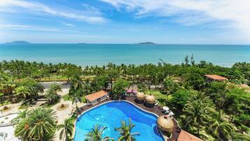 Un resort con piscina, palmeras y vista al océano.