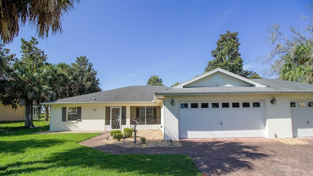 A two-story house with a garage, a well-maintained lawn, and a small garden area. - Four Bedroom Comfort  4668 Home by RedAwning (Hernando)