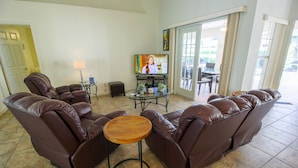A living room with a brown leather sofa, a wooden coffee table, and a television on a stand. - Four Bedroom Comfort  4668 Home by RedAwning (Hernando)