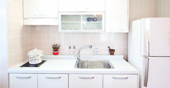 Cocina con armarios blancos, un lavabo, una estufa y un refrigerador.