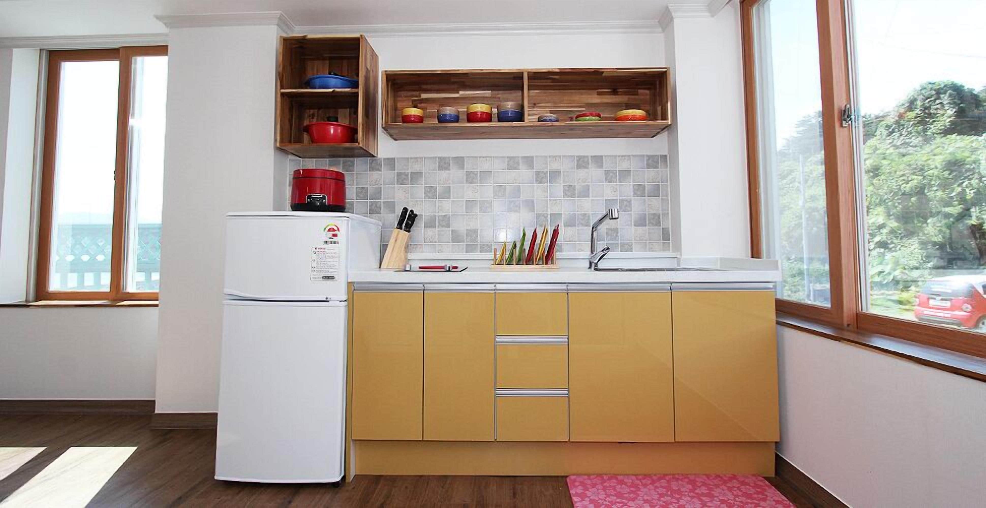 Una cucina compatta con frigorifero bianco, mobili in legno e piastrelle a parete.