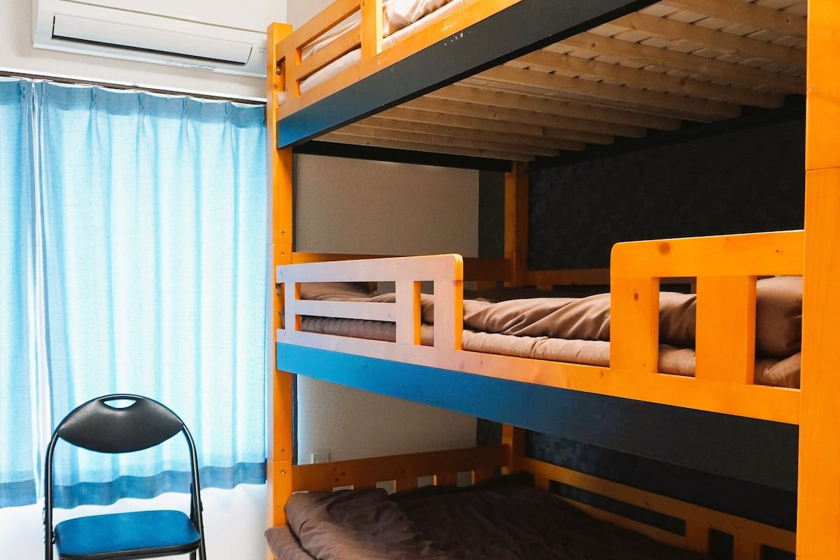 Une chambre avec un lit superposé, une chaise et un appareil de climatisation.
