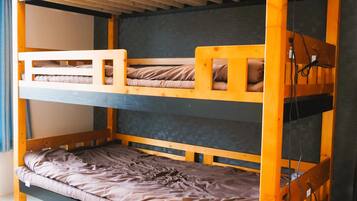 A bunk bed with three levels, wooden headboards, and a grey mattress on the bottom bunk.