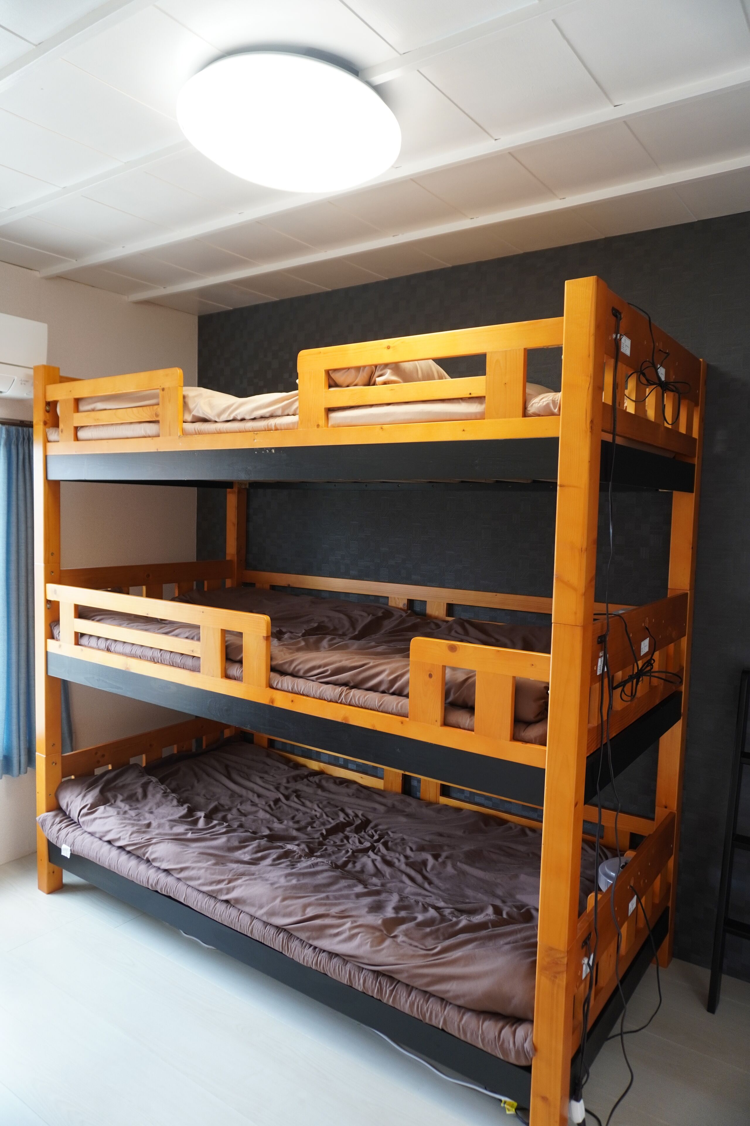 A bunk bed with three levels, a ceiling light, and a power outlet on the side.