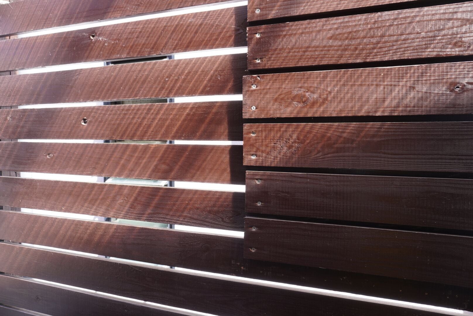 Una cerca de madera con listones horizontales y tornillos a la vista.
