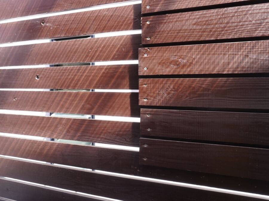 Una cerca de madera con listones horizontales y tornillos a la vista.
