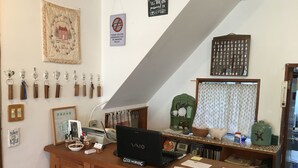 A reception desk with a laptop, papers, and a coffee machine. There are keys hanging on the wall, a no-smoking sign, and a framed picture. - Pension Cocotte (Takayama)