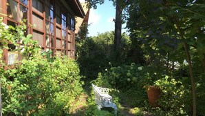 A garden with a white metal bench, a large potted plant, and a building with large windows. - Pension Cocotte (Takayama)
