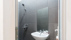 A bathroom with a white sink, a mirror, and a shower.