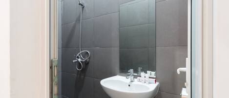 A bathroom with a white sink, a mirror, and a shower.
