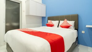 A neatly made bed with a white and red bedspread, two pillows with red and white patterns, and a grey headboard.